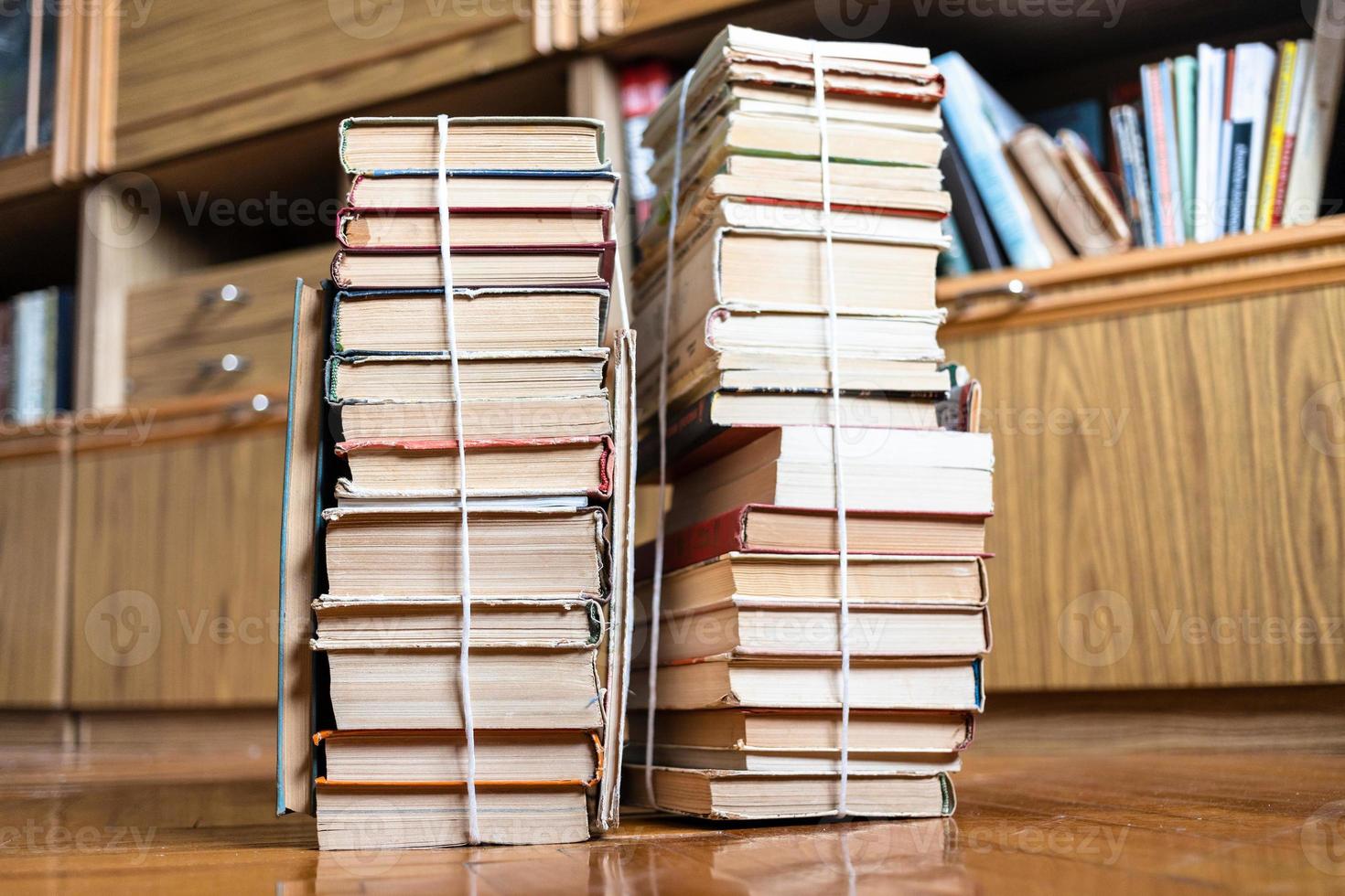two stacks of old books tied with twine on floor photo