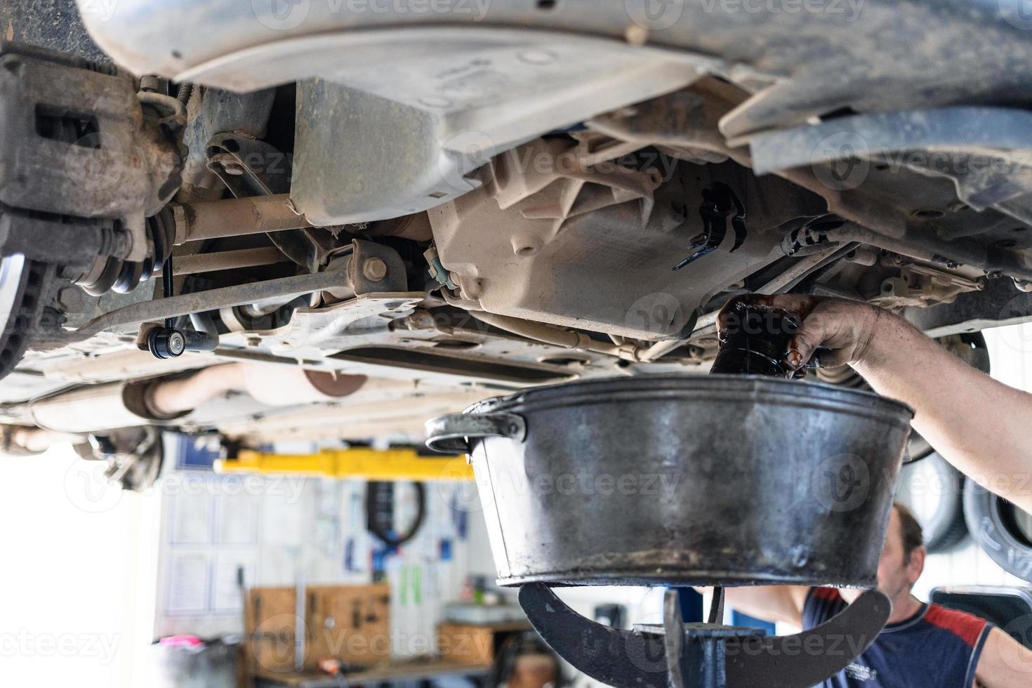 draining old engine oil from car in car workshop photo