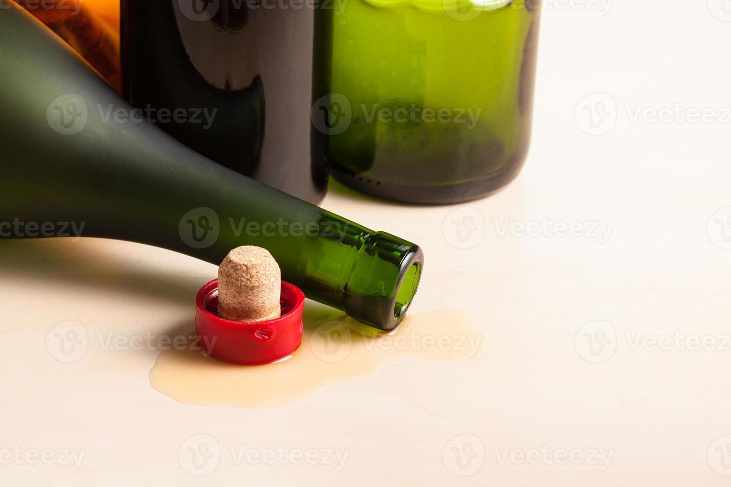 overturned bottle and cork near empty wine bottles photo