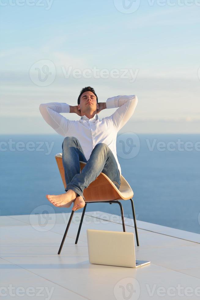 relaxed young man at home on balcony photo