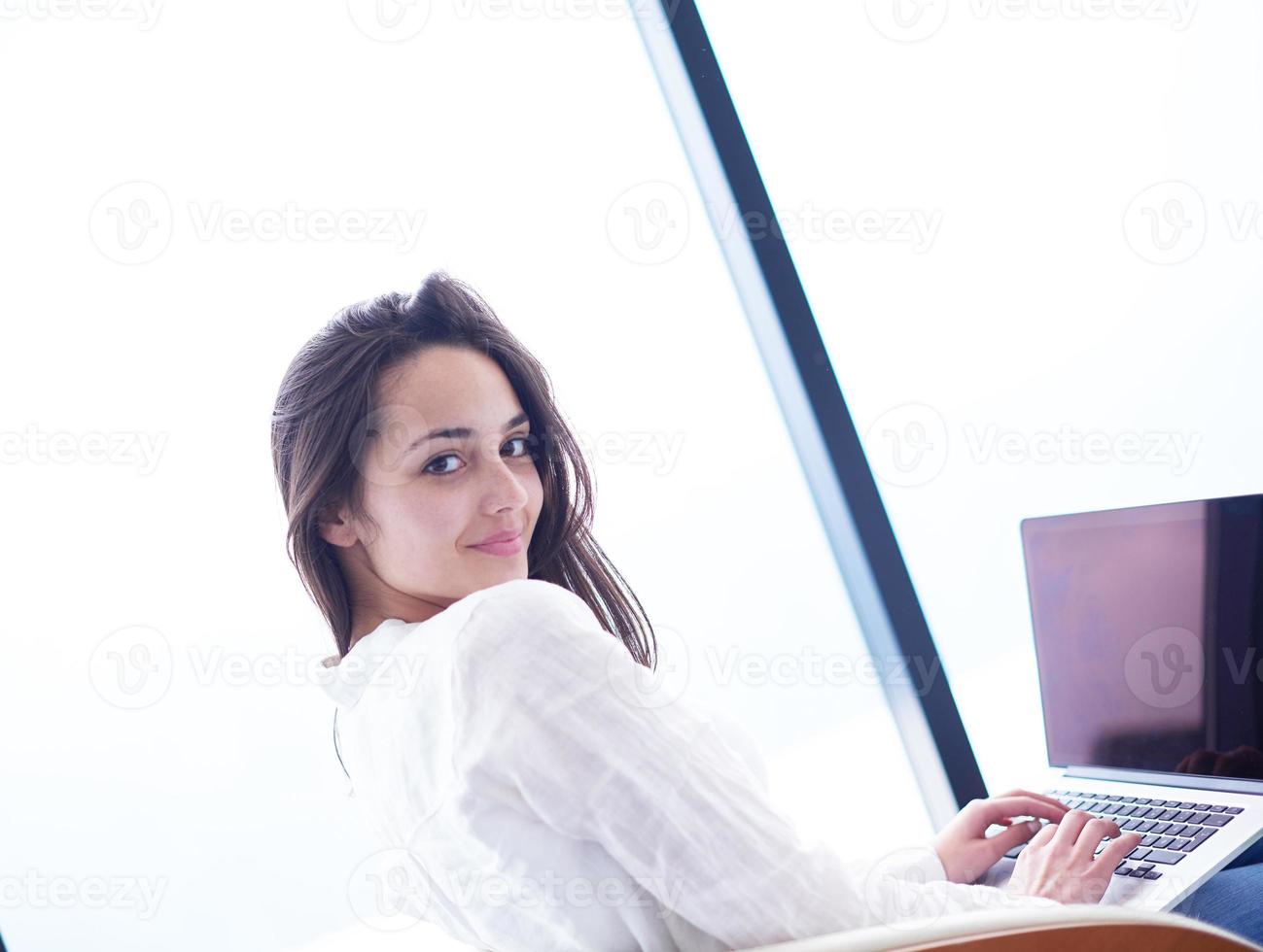 relaxed young woman at home working on laptop computer photo