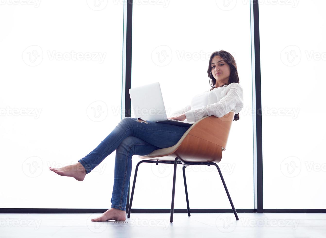 relaxed young woman at home working on laptop computer photo