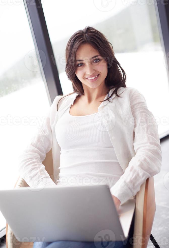 relaxed young woman at home working on laptop computer photo