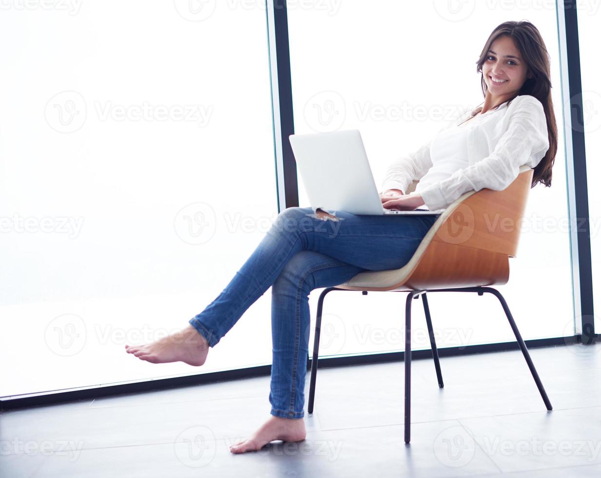 relaxed young woman at home working on laptop computer photo