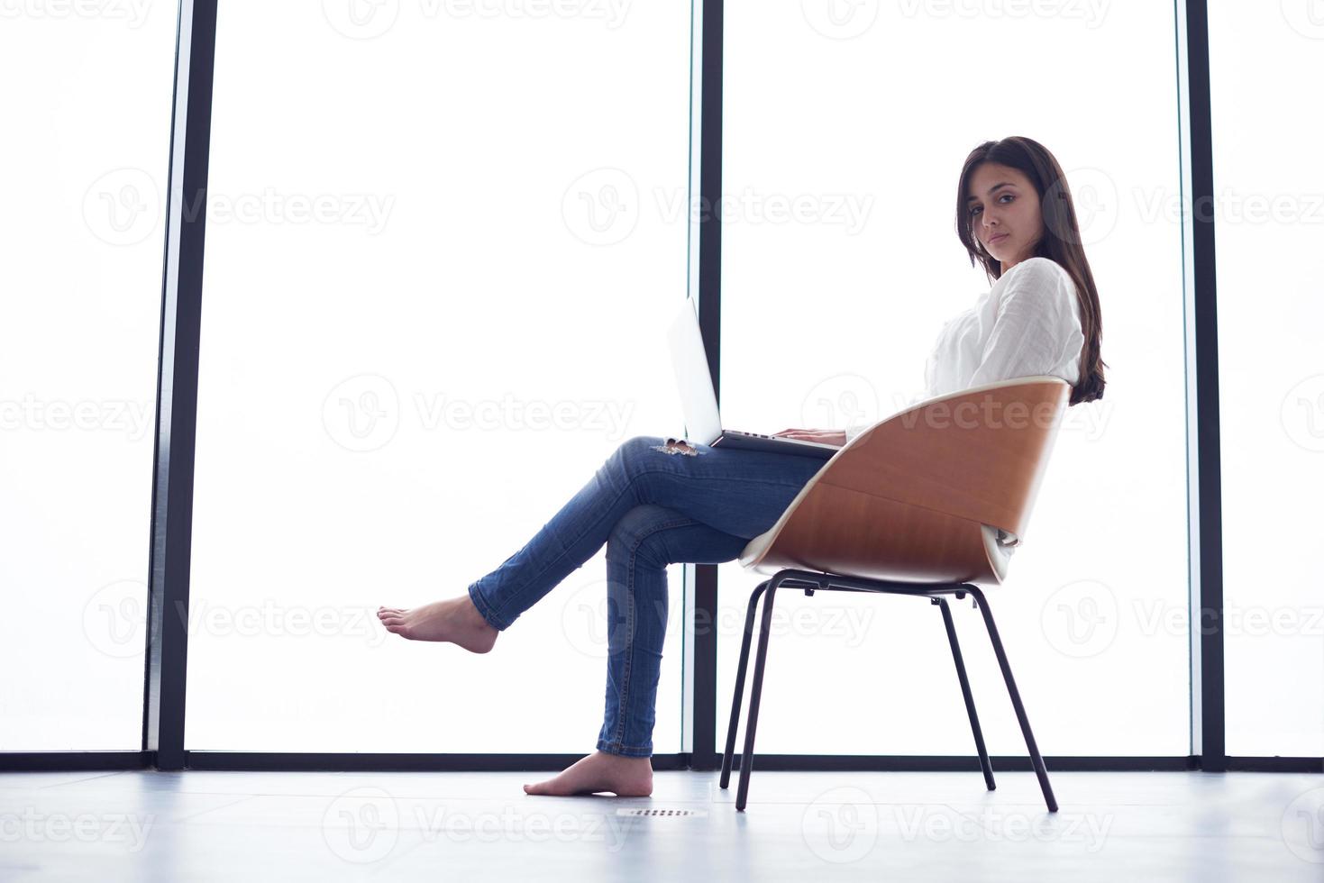 relaxed young woman at home working on laptop computer photo