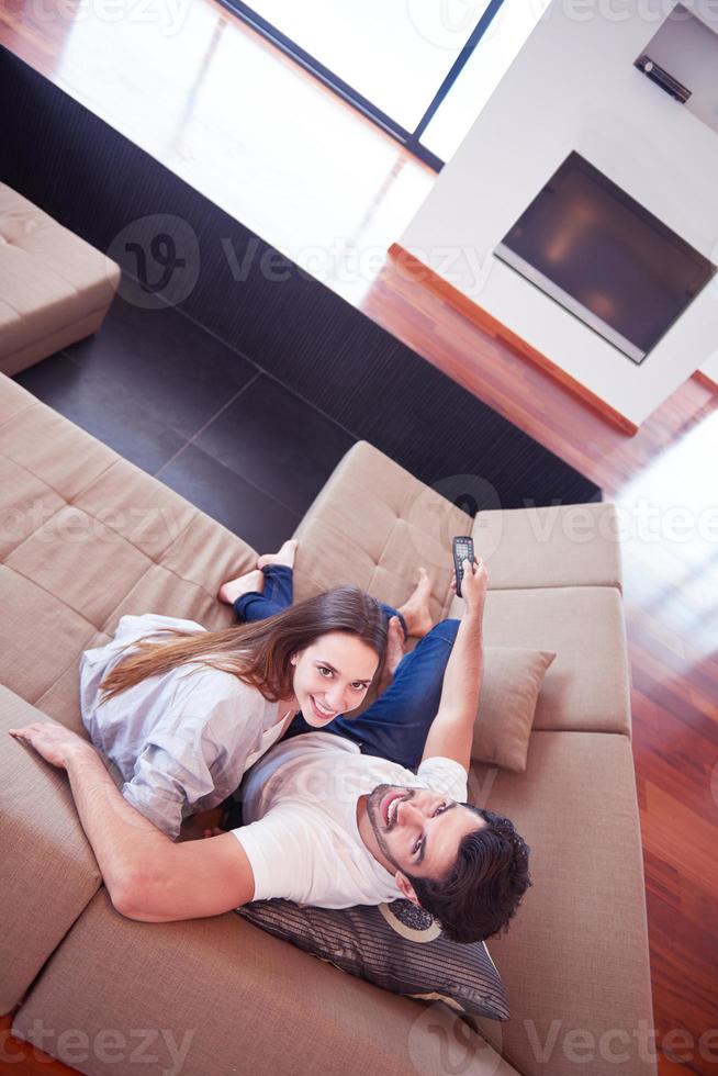 young couple watching tv at home photo