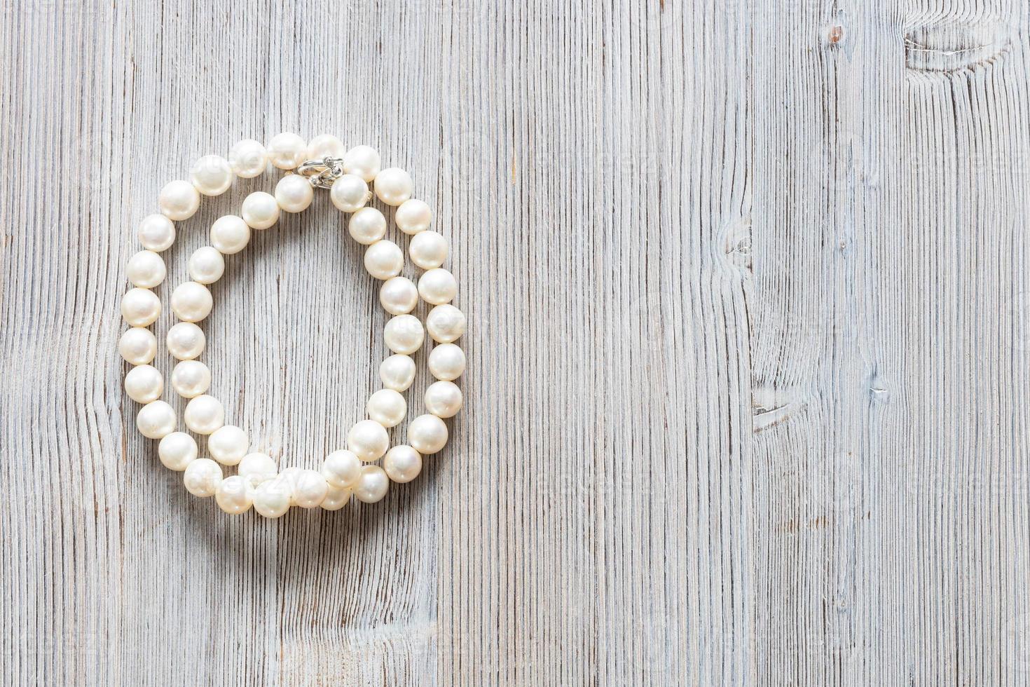 collar de perlas blancas en madera gris con copyspace foto