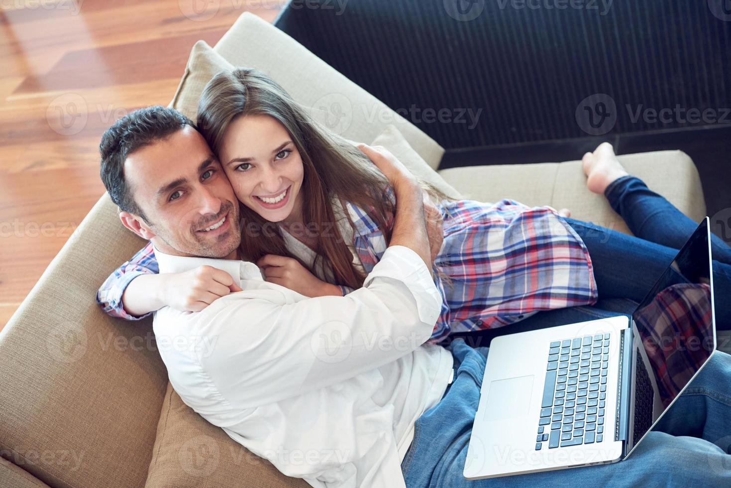 relaxed young couple working on laptop computer at home photo