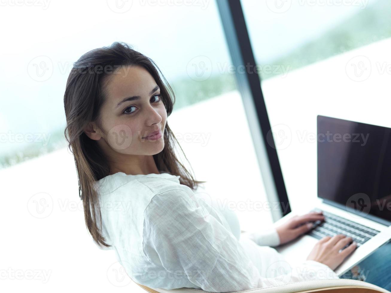 relaxed young woman at home working on laptop computer photo