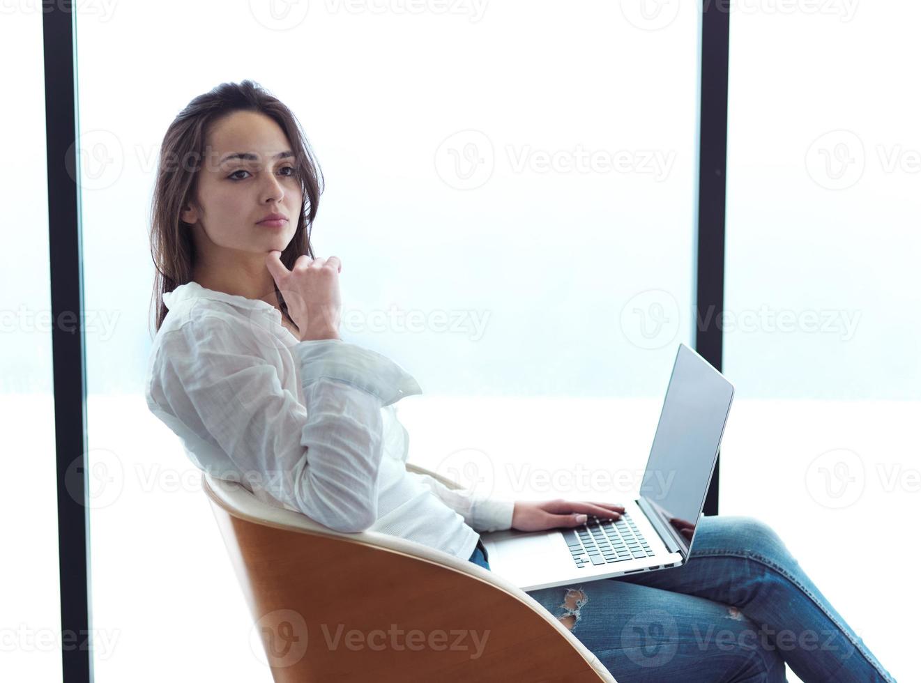relaxed young woman at home working on laptop computer photo