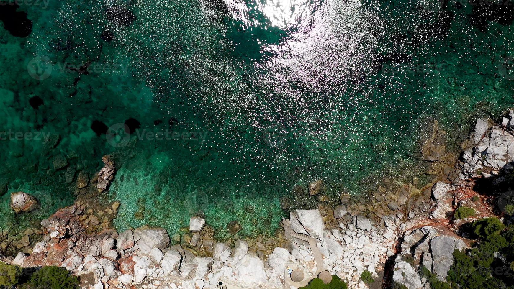 vistas aéreas de drones sobre una costa rocosa, aguas cristalinas del mar Egeo, playas turísticas y mucha vegetación en la isla de skopelos, grecia. una vista típica de muchas islas griegas similares. foto