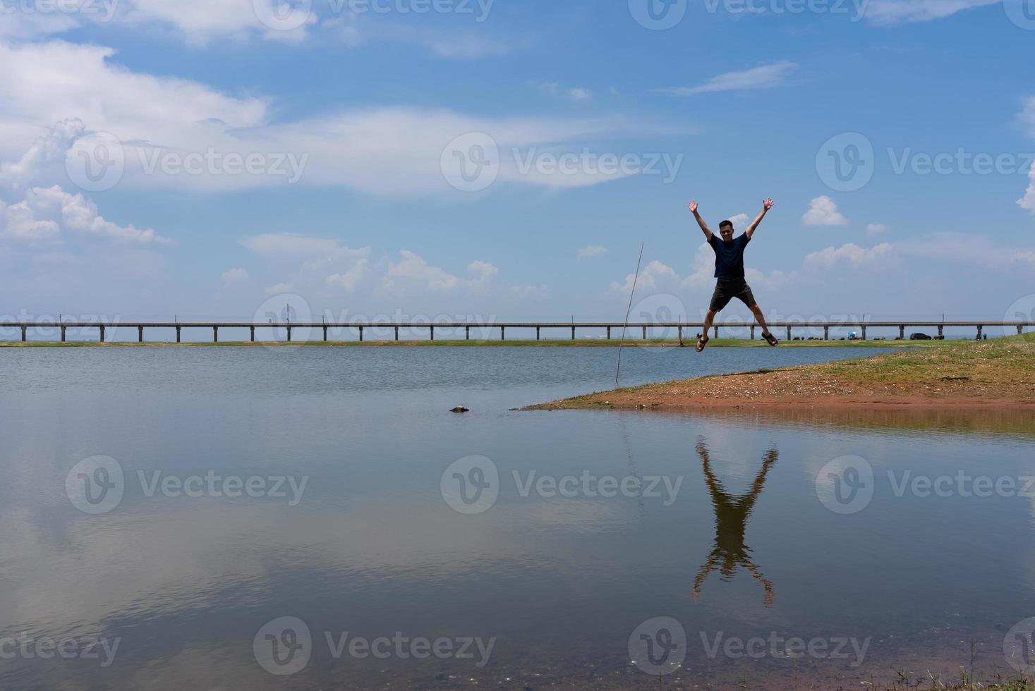 Asian Man Jumping Over Lake While Travel to Lopburi Thailand in Summer Vacation photo