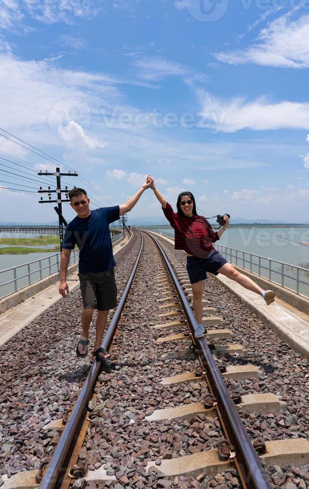 Asian Couple Walking Together on RailRoad While Travel on Summer Vacation photo
