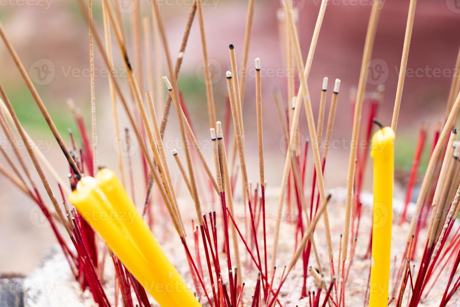 Close up View of Incense and Candles in Joss Stick Pot in Buddhist Temple photo