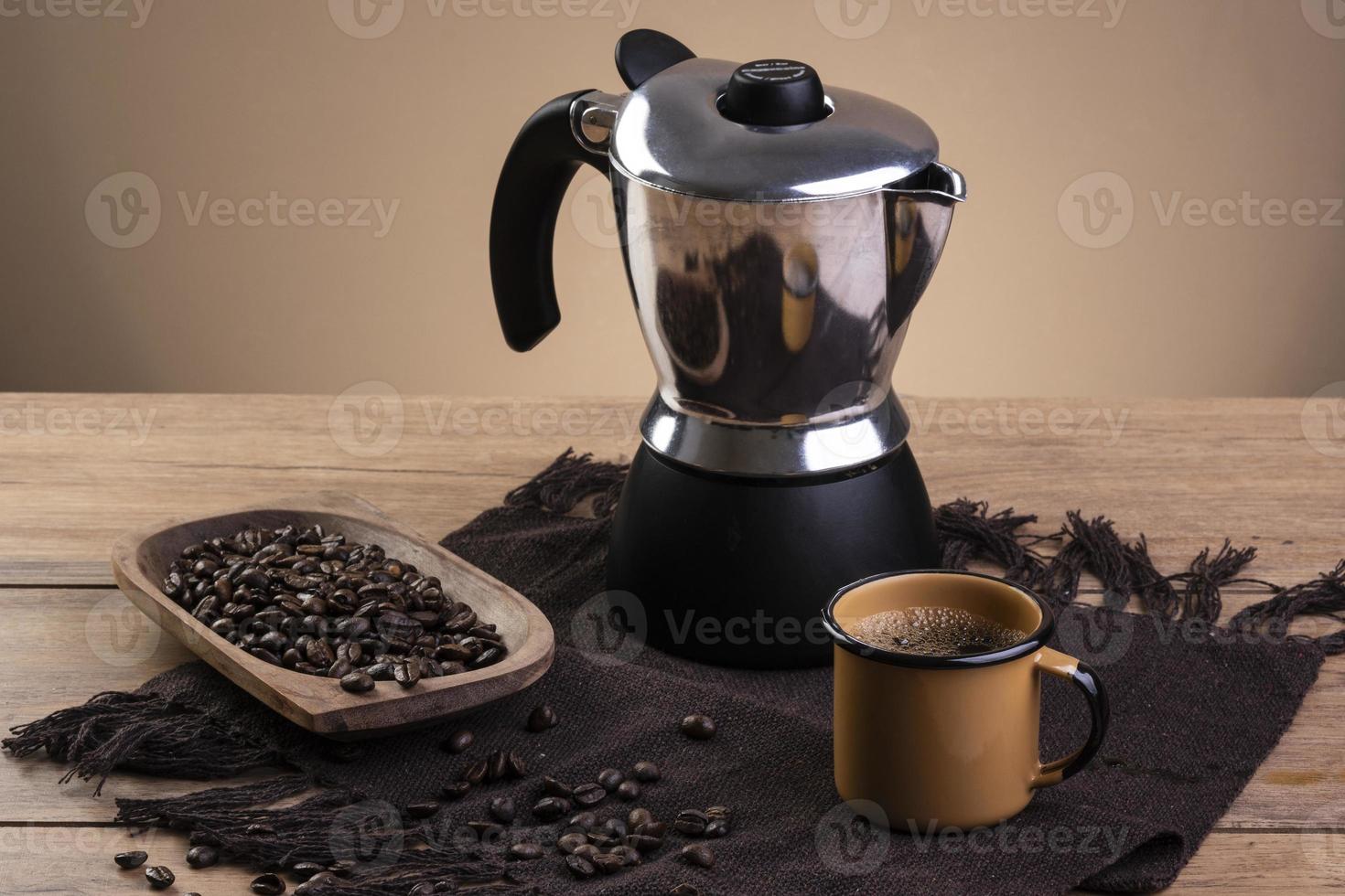 cafetera italiana y una taza de café con granos de café tostados en un  recipiente de madera 10841144 Foto de stock en Vecteezy