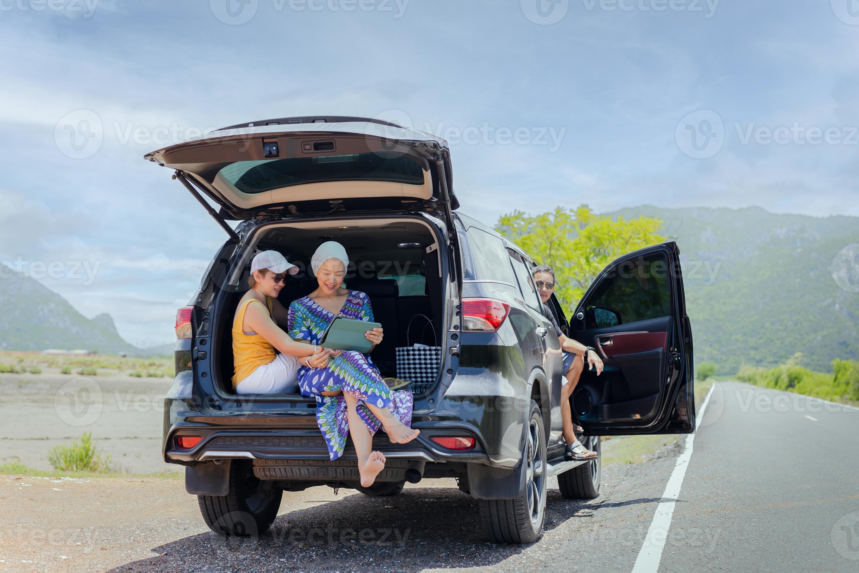 Group of of friend sitting in open trunk of a black car looking at