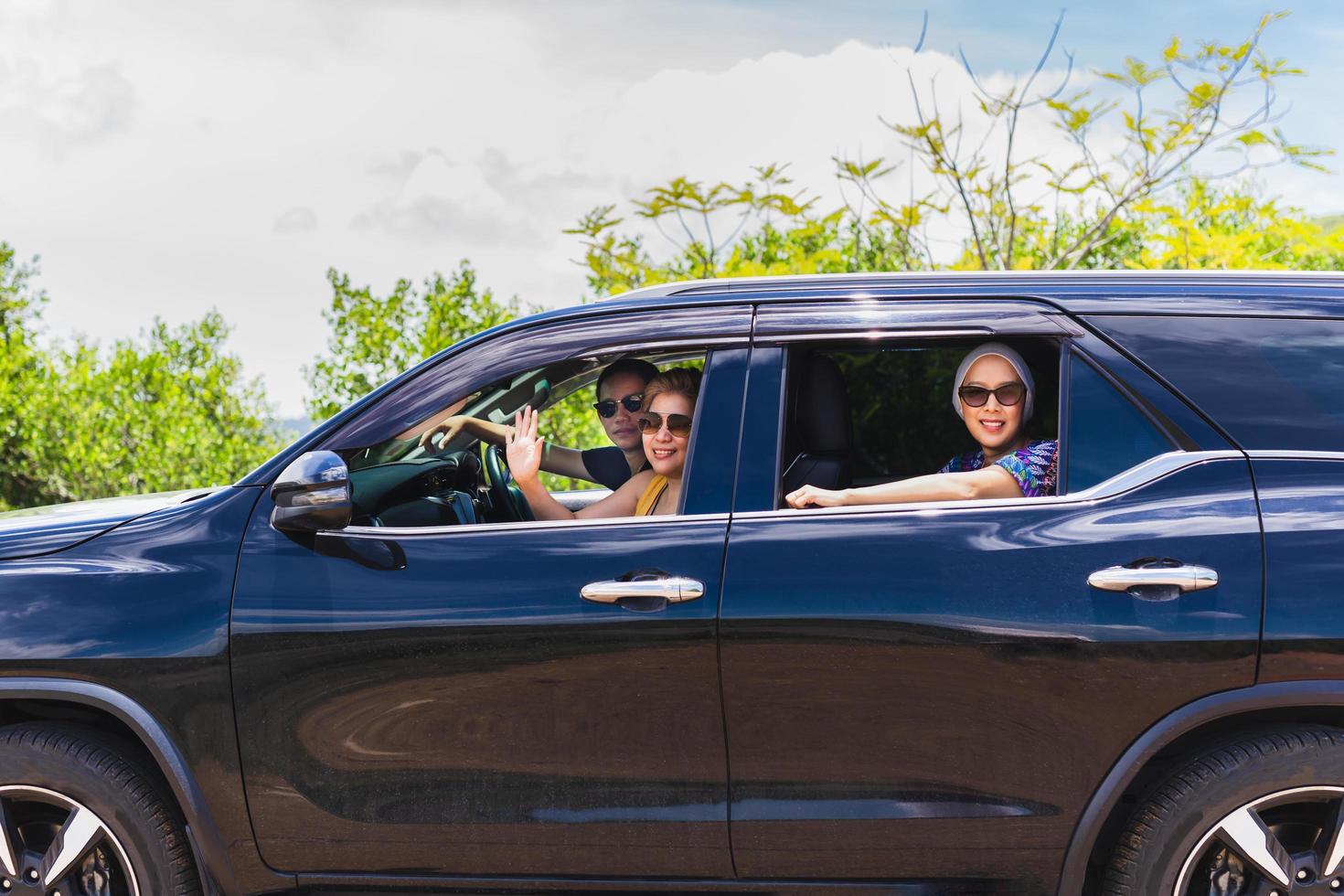 Three best friends enjoying traveling in the car on a road trip. photo