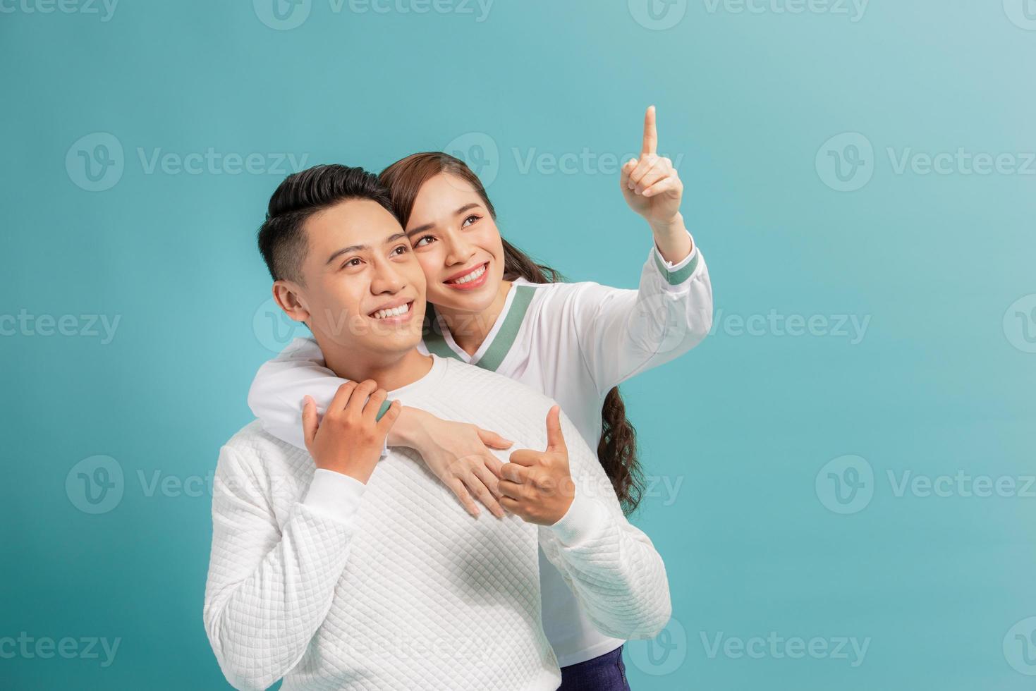 beautiful young happy couple love smiling embracing point finger to empty copy space, man and woman smile looking up, photo