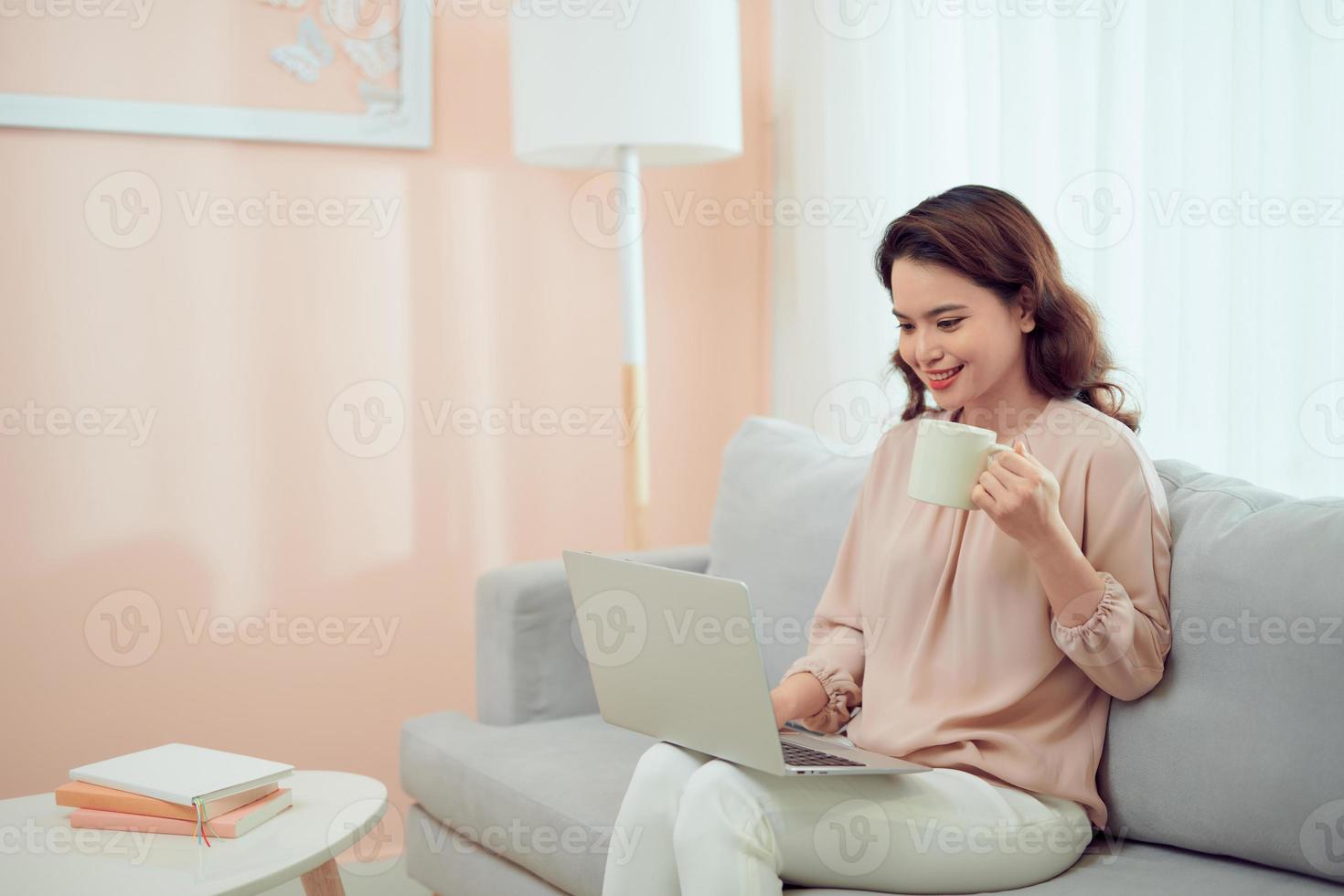 concepto de la mañana. mujer independiente emocionada tomando café en casa y usando una computadora portátil, trabajando en línea, espacio libre foto