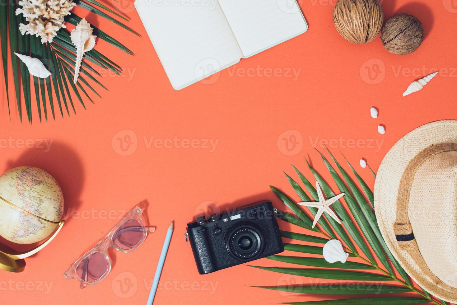 Flat lay beach accessories sunglasses, hat, camera with palm branches and shells. photo