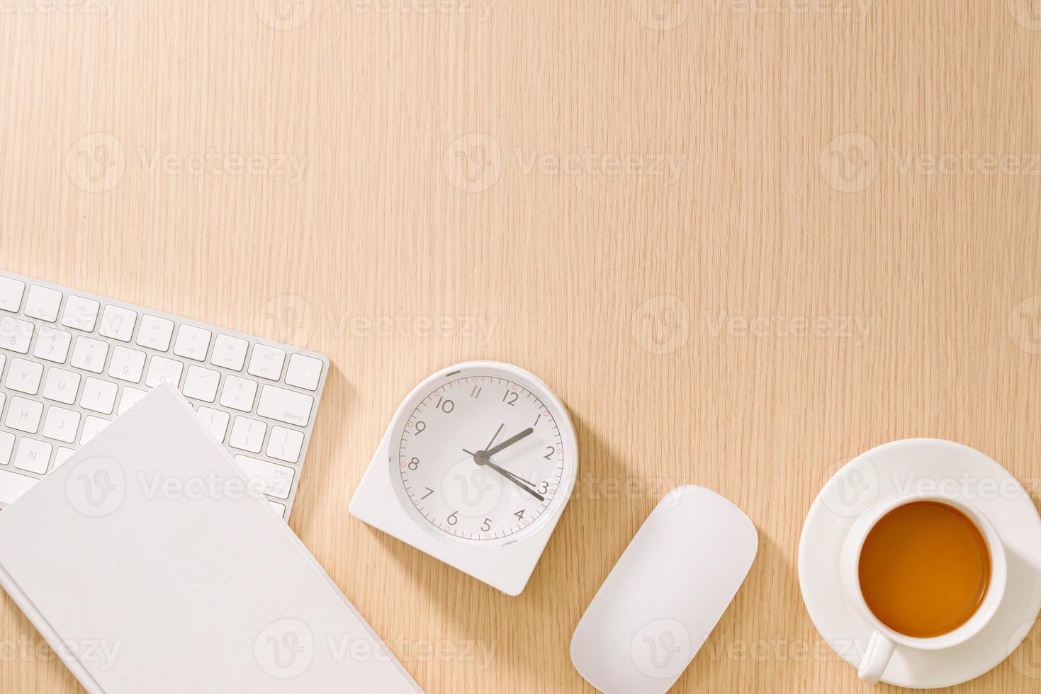Modern white office desk with keyboard, mouse, notebook, clock and cup of coffee. Top view with copy paste. Business and strategy concept mockup. photo