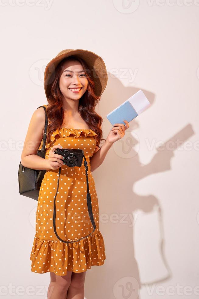 Expressive tourist woman in summer casual clothes, hat holding passport, tickets isolated on beige background. Female traveling abroad to travel weekends getaway. Air flight journey concept photo