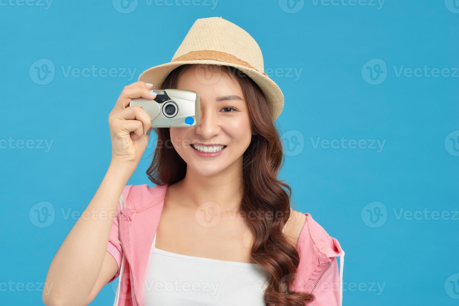 atractiva mujer asiática enérgica sosteniendo felizmente cemara aislada en el fondo azul del estudio foto