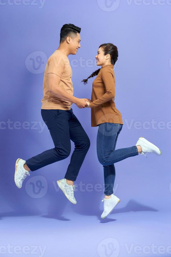Attractive  partners holding hand jumping having fun isolated on purple background photo