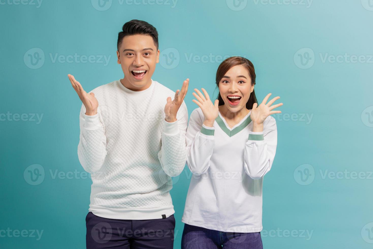 As like as two peas. A wonderful couple are posing with their palms near their chins, looking in the camera with surprised facial expressions photo