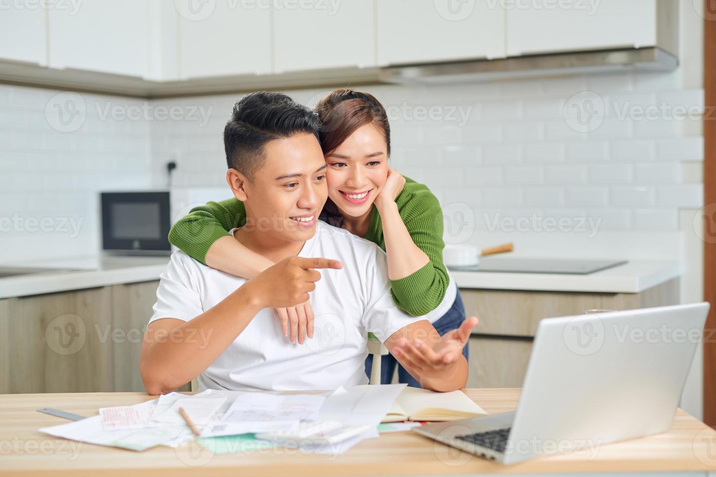 feliz pareja joven esposo y esposa usando una computadora portátil mirando la pantalla pagar facturas en línea en la aplicación calcular el pago de la inversión hipotecaria foto