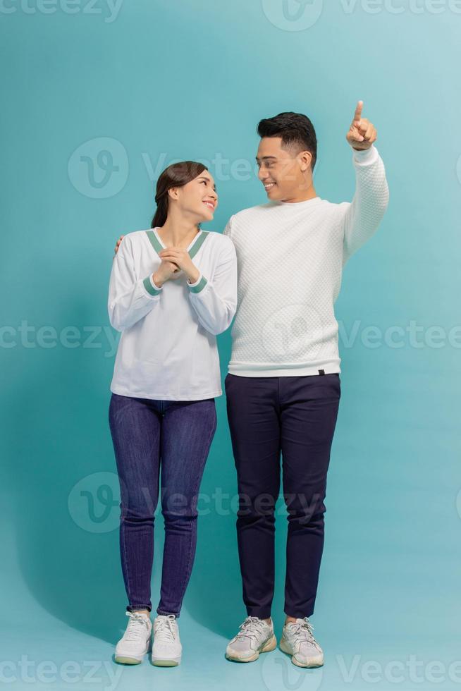 Portrait of lovely surprise cheerful adorable young nice couple boy pointing with his finger to far away, girl shows stunning photo