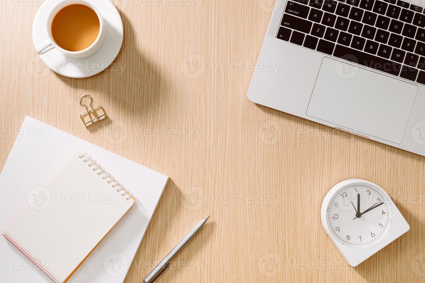 mesa de escritorio de oficina con computadora portátil, teléfono inteligente, taza de café, bolígrafo, lápiz y cuaderno. artículos de oficina y aparatos en la mesa del escritorio. concepto de mesa de escritorio de trabajo. foto