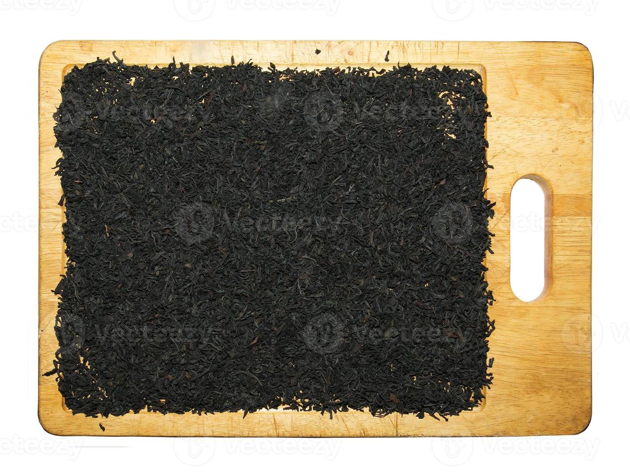 Black tea is placed on a wooden board in a thin layer to dry. Isolated on white background. photo