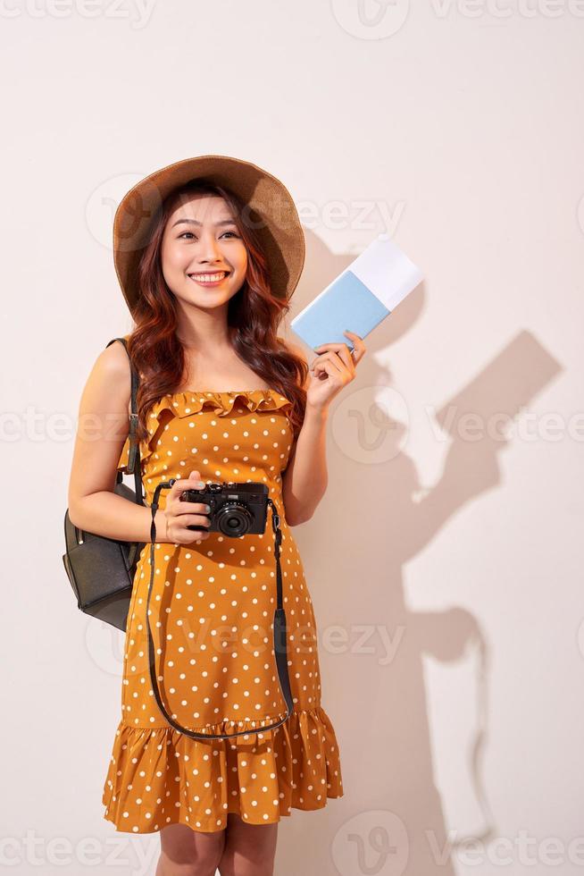 Expressive tourist woman in summer casual clothes, hat holding passport, tickets isolated on beige background. Female traveling abroad to travel weekends getaway. Air flight journey concept photo