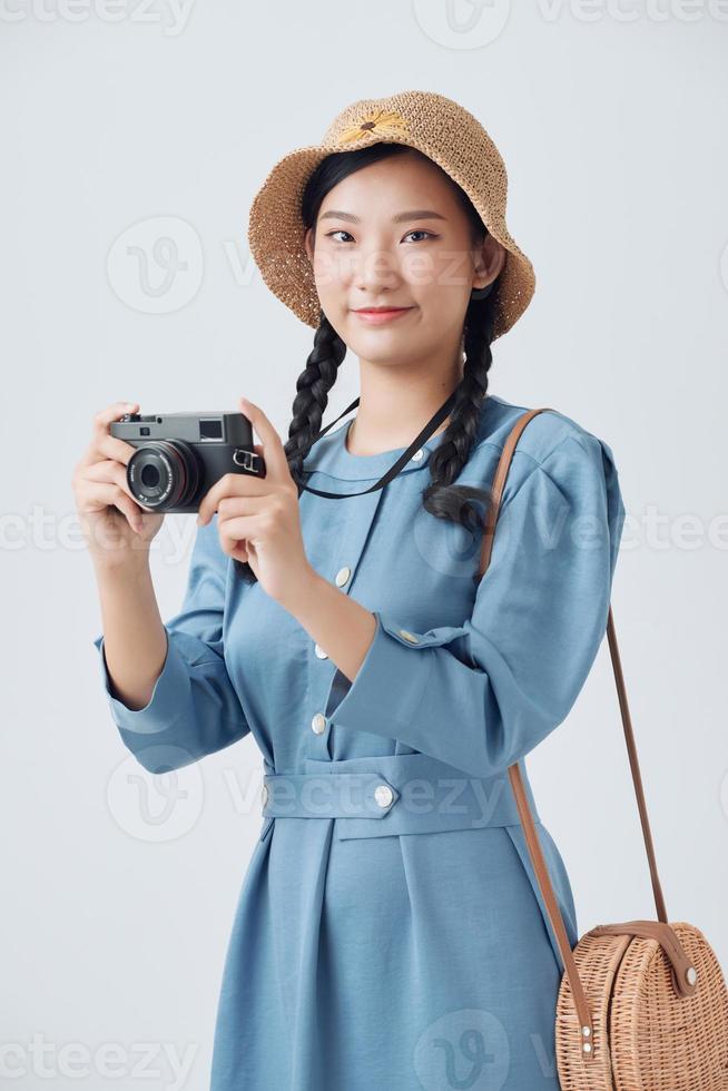 Young beautiful Asian backpack traveler woman using digital compact camera and smile, looking at copy space photo