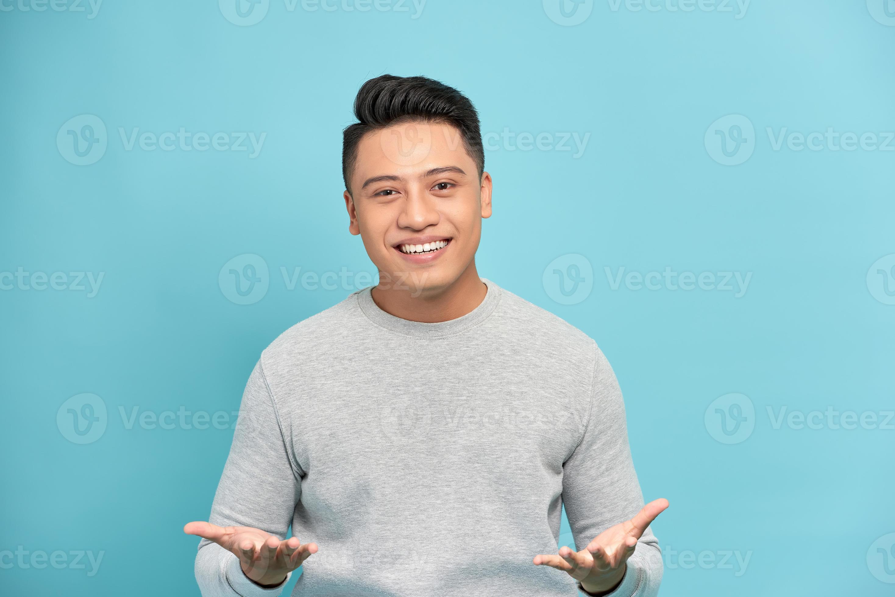 Young happy handsome Asian man raising his hands with open palms