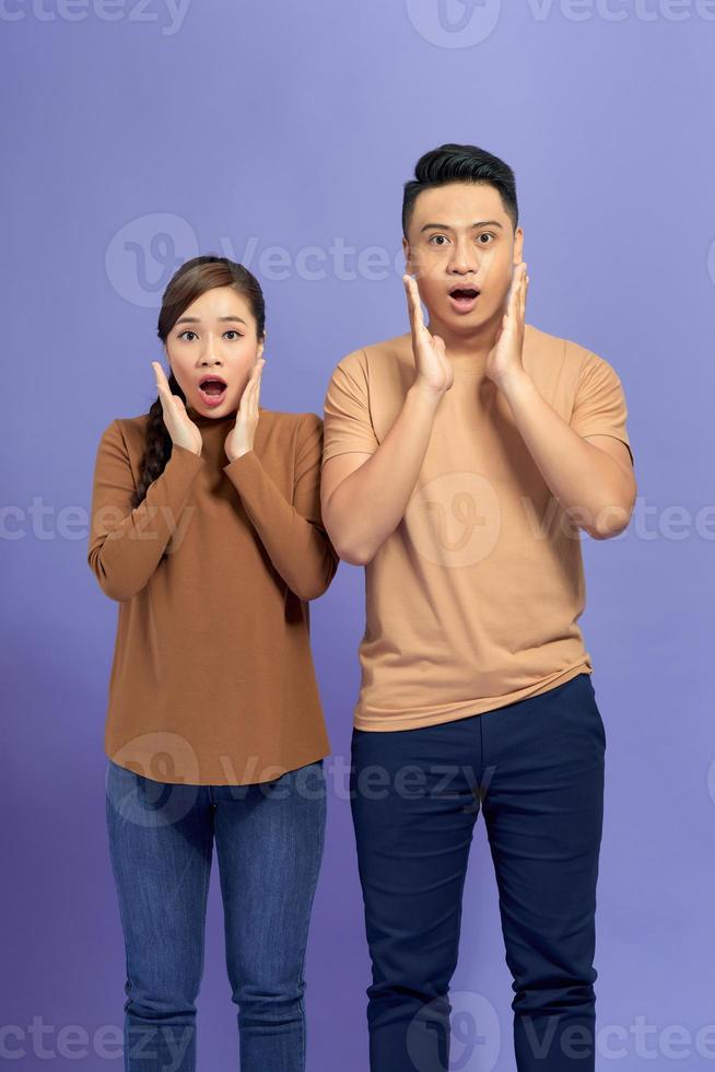 Amazed asian couple expressing shock, purple studio background photo
