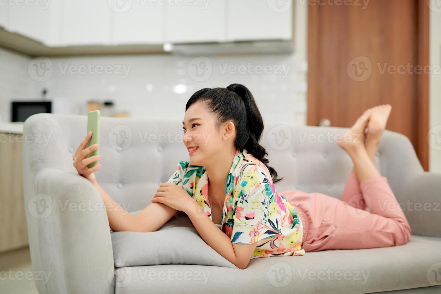 Asian woman reading text on couch at home in the living room photo