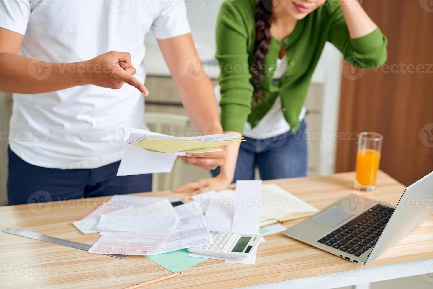 Angry young couple arguing by their many debts at home. Financial family problems concept. photo