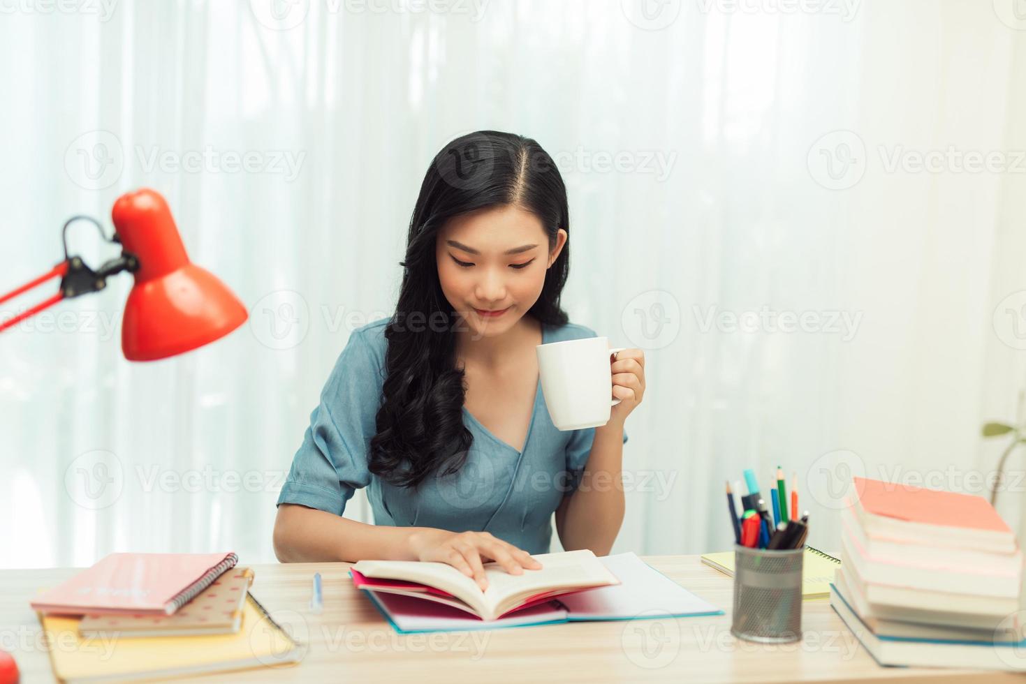 tiempo libre. mujer joven con gafas leyendo un libro sentada en casa, bebiendo té, foto