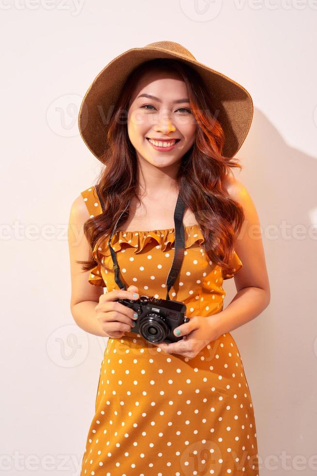 Image of young photographer woman isolated over beige background wall holding camera. photo