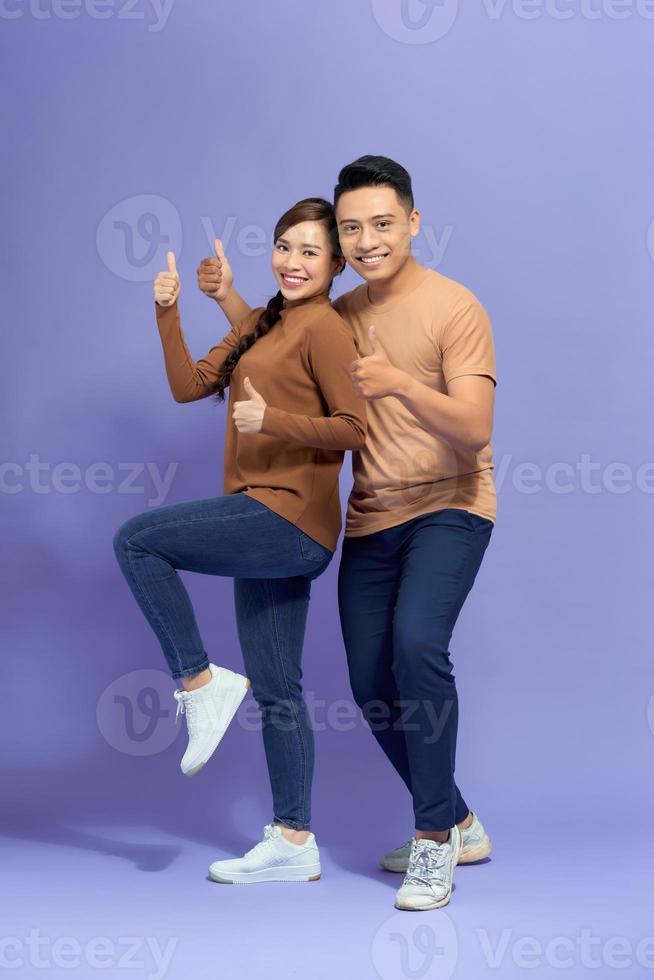 Happy young couple showing thumbs up and looking at camera photo