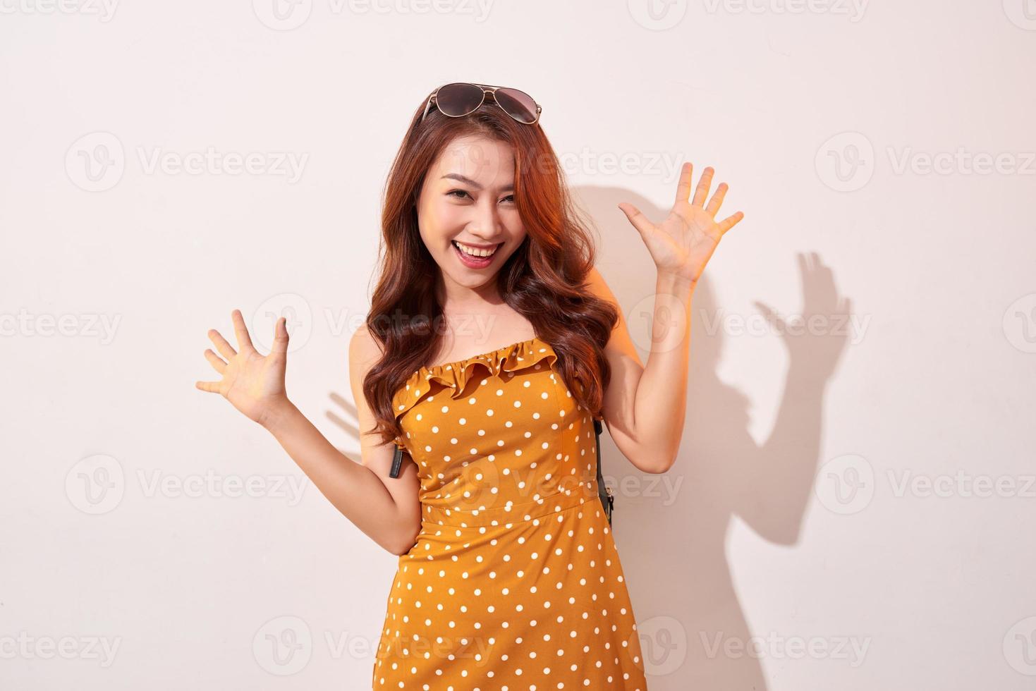 retrato de una chica de moda alegre que se vuelve loca con un vestido de lunares naranja aislado en beige foto