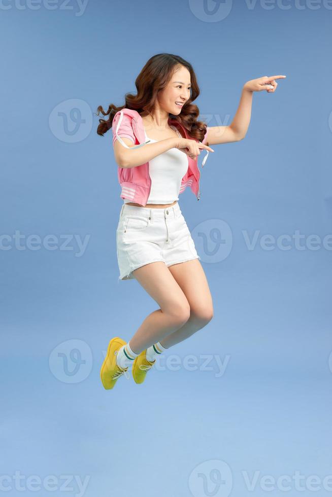 Cheerful hipster girl jumpig with hands spread wide over  background. Young woman in jump. photo