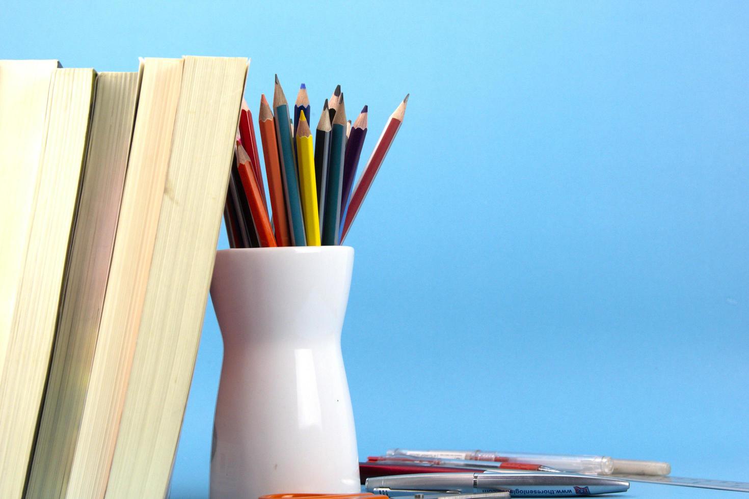 conceptos de regreso a la escuela con libros aislados, bolígrafos, lápices sobre fondo azul claro. utilizado en el afiche de regreso a la escuela, diseño de plantilla de folleto para elementos educativos foto