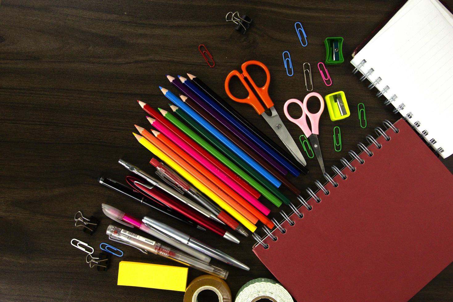 Red Books with color pencils and education elements, back to school concepts on dark wood background photo