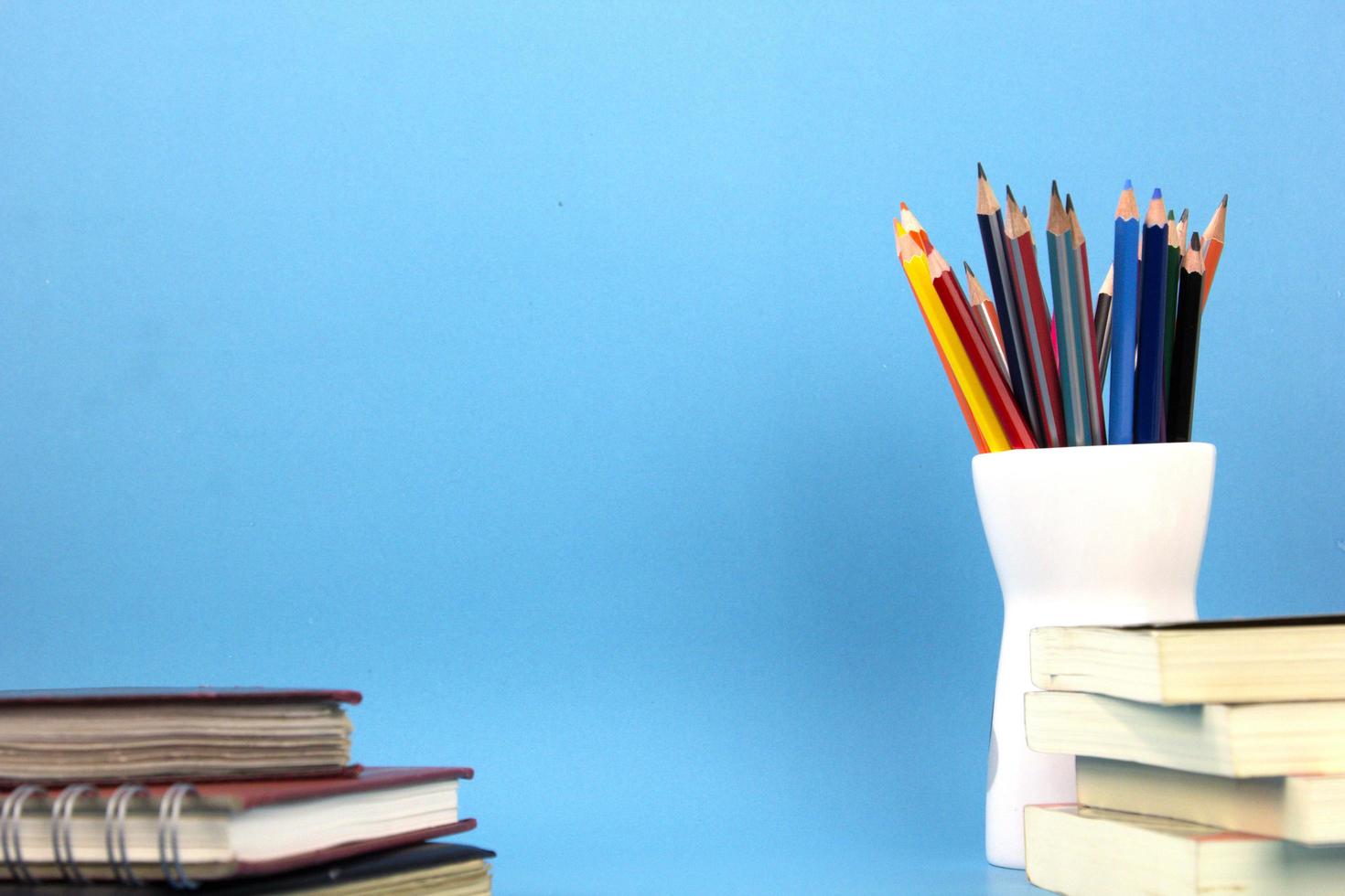 elementos educativos libros, bolígrafos, lápices aislados sobre fondo azul claro. utilizado en el cartel de regreso a la escuela, diseño de plantilla de folleto foto