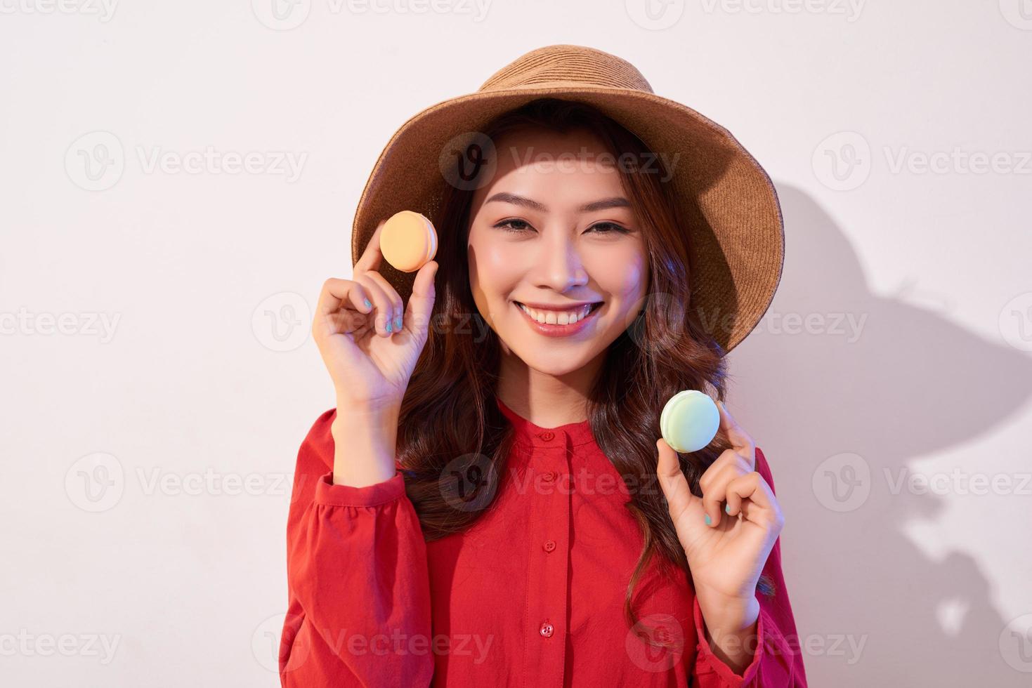 Young woman standing with french sweet cookie macaron over white background photo