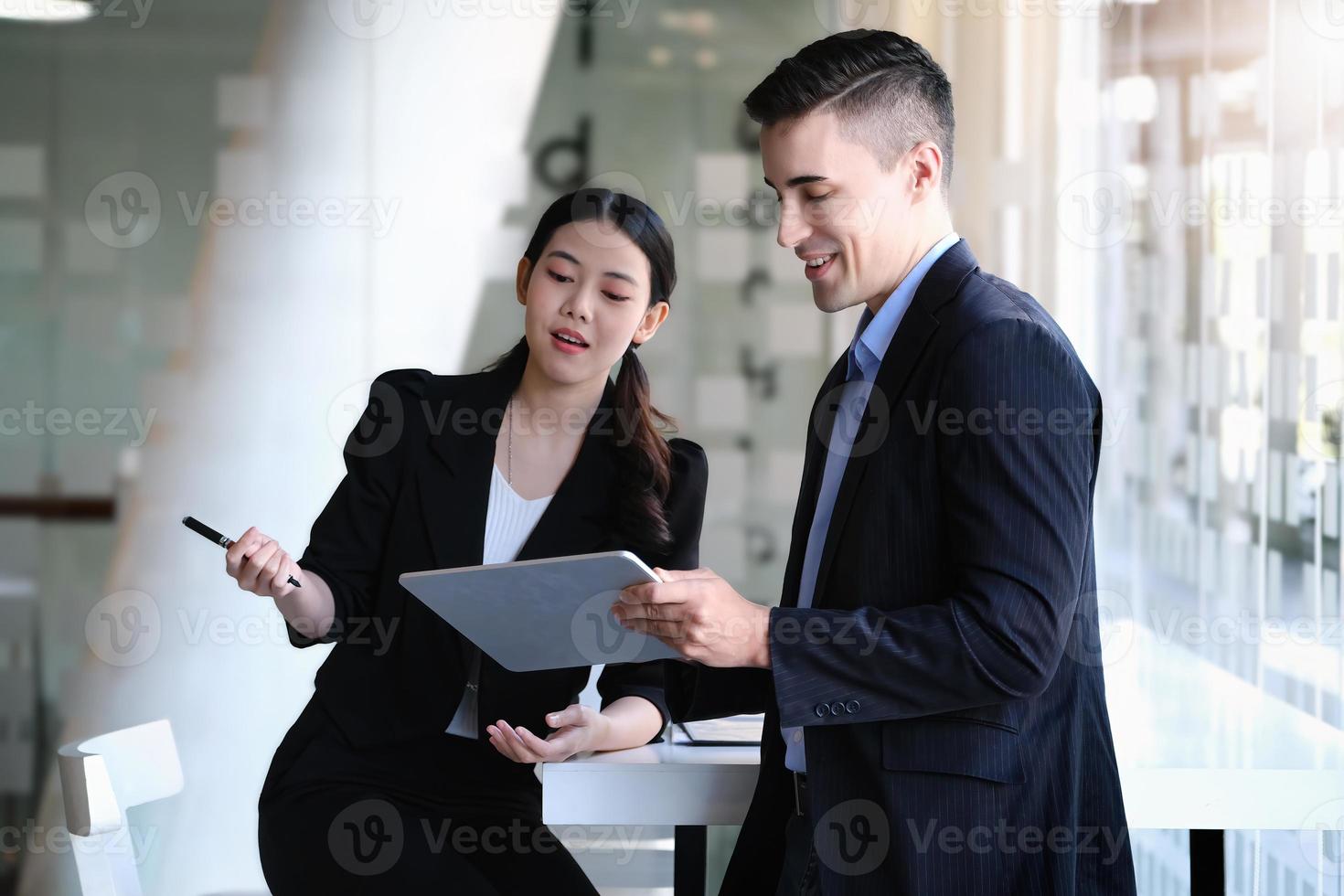 At the consultation, a male adviser using tablet to explain the profit restructuring to female business owners. photo