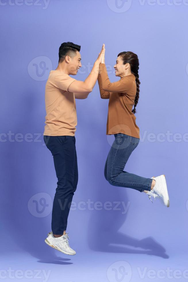 Photo of cheerful couple jump give highfive celebrate victory on purple background